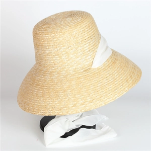 Detail of fine straw weave texture and white ribbon tie on a sun hat for summer
