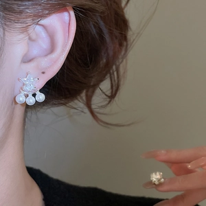 Dettaglio degli orecchini a stella in argento con zirconi e perle pendenti sul modello