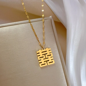 Detailed close-up of a gold titanium steel necklace with a Xi character pendant on silk