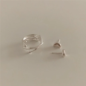 Detailed view of irregular silver textured ring and minimalist bean stud earrings