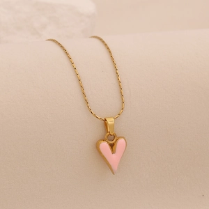 Collier doré avec pendentif cœur rose sur fond beige, design minimaliste de style français