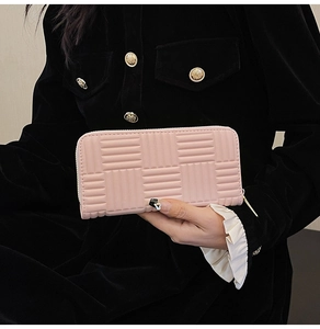 Pink long wallet for women with geometric texture held by a model in a professional shot
