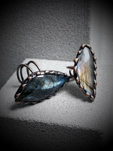 Macro shot of two antique bronze labradorite rings with blue and gold flashes on grey foam