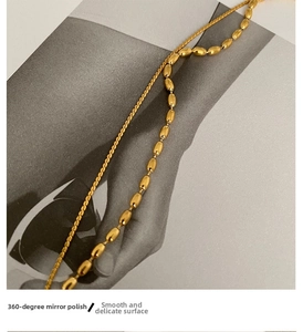 Close-up of dual-layer 18K gold plated chain with polished beads on a fashion magazine