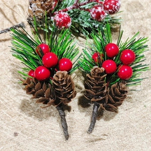 Detail of Christmas pine needles with red berries and pine cones on burlap background