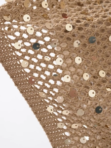 Vue macro d'un tricot au crochet marron avec paillettes dorées et motifs ajourés