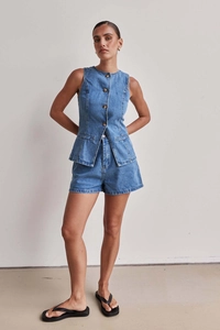 Dettaglio della trama del denim blu e bottoni in metallo sul set coordinato a vita alta