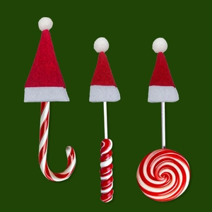 Close-up of candy canes and lollipops wearing festive mini red felt Christmas hats
