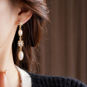 Close-up of elegant gold tassel earrings with pearls and rhinestones on a model