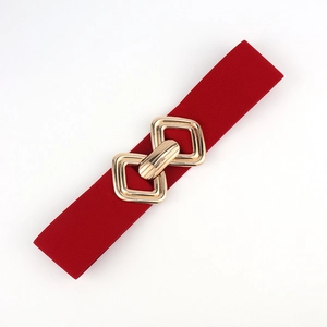 Détail d'une ceinture élastique rouge avec boucle métallique géométrique dorée entrelacée