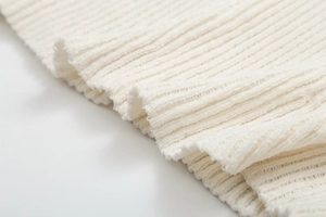 Macro close-up of premium white ribbed knit fabric texture and rolled edge details