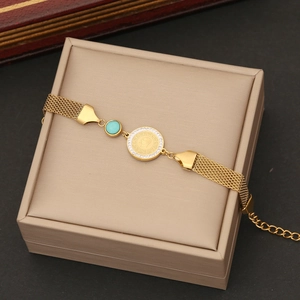 Détail d'un bracelet en maille dorée avec perle turquoise et pendentif pièce