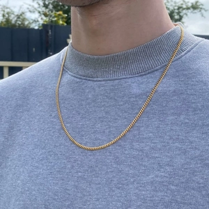 Close-up of a man wearing a double-layered gold stainless steel chain necklace outdoors