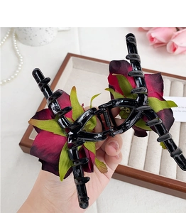 Close-up of elegant dark red fabric rose flower on black plastic claw hair clip