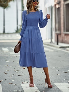 Détail d'une robe midi bleue à manches longues avec corsage froncé et jupe à plusieurs niveaux