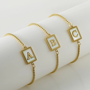 Gold stainless steel chain bracelets with shell alphabet charms A B C on a white stand