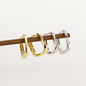 Macro view of geometric square earrings in gold and silver finish on white background