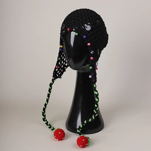 Detail of hollow knit beanie with colorful beads and red crochet strawberry charms