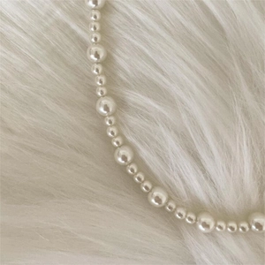 Detailed close-up of mixed sized white pearls on soft faux fur background