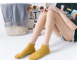 Detail of yellow cotton ankle sock with cartoon embroidery on model with Nordic decor