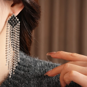 Macro shot of long rhodium tassel earrings with sparkling rhinestones and black gemstone