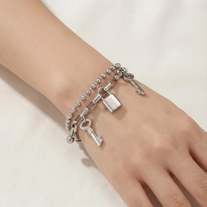 Detail of silver double-layered bead chain bracelet with padlock and key charms