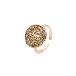 Detail of adjustable gold ring featuring a religious Saint Benedict medal with purple crystals