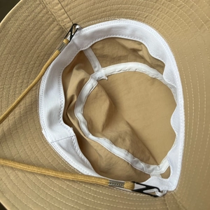 Detail view of khaki bucket hat interior with white sweatband and adjustable yellow cord