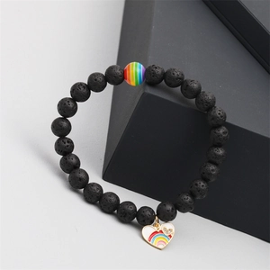 Detailed shot of a black volcanic lava stone bracelet with a rainbow heart charm