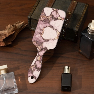 Detailed close-up of marble pattern hairbrush with pink-purple texture on wooden background