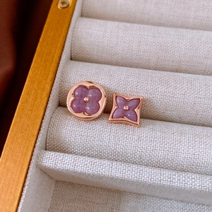 Macro view of rose gold floral earrings with purple zircons in a wooden jewelry box