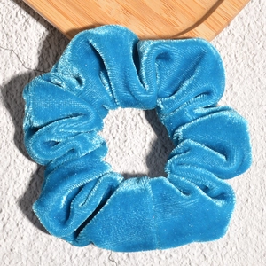 Close-up of royal blue velvet scrunchie showing soft pleated texture and rich luster
