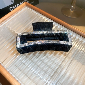 Detail of square black velvet hair claw clip with shimmering rhinestone edges on a tray