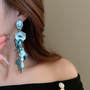 Close-up of long light blue pleated petal tassel earrings on model showing glossy texture