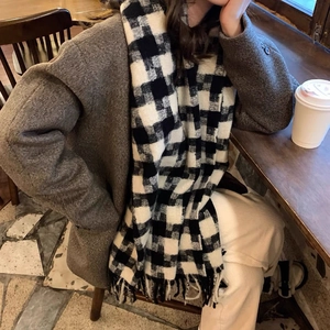 Close-up of black and white plaid scarf with fringe details in a cafe setting