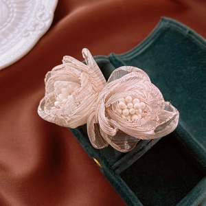 Detail view of handmade lace flower earrings with pearls on green velvet jewelry box