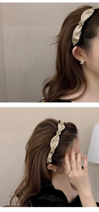 Detail of beige pleated fabric headband decorated with gold flowers and pearls