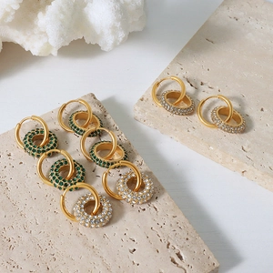 Elegant gold-plated titanium earrings with green crystals on minimalist travertine stone