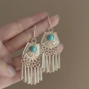 Dettaglio di orecchini bohémien in argento con pietre turchesi e lunghe nappe in metallo