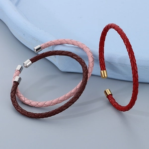 Dettaglio di bracciali rigidi in pelle intrecciata rosa, marrone e rossa con chiusura