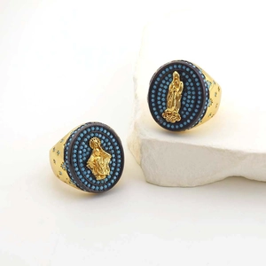 Macro shot of gold Virgin Mary oval rings with blue turquoise beads on white stone