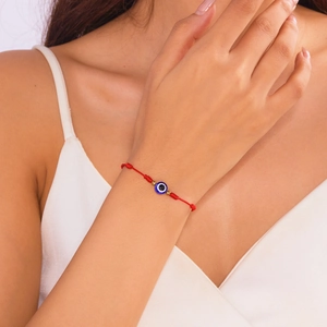 Handmade red braided evil eye lucky bracelet with golden beads on wrist for couples