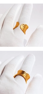Detail of matte gold ring with wavy leaf texture on a gloved finger with open design