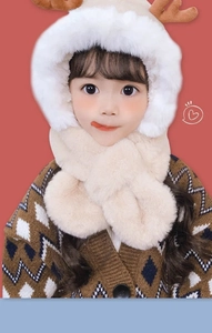 Detailed close-up of beige plush children's winter hat with deer antlers and soft scarf