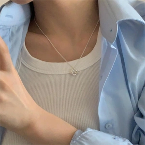 Close-up of minimalist 925 sterling silver hollow heart pendant necklace on collarbone