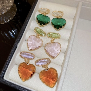 Detail view of heart crystal earrings in green, pink and amber with gold metallic frames