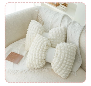 Detail of white wave puff grid pillows with bone-shaped texture on a soft sofa