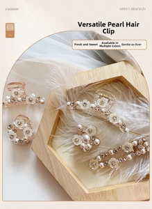 Detailed close-up of white resin flower hair clips with pearls and rhinestones on wood
