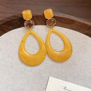 Macro view of geometric resin drop earrings featuring yellow tones and vintage design