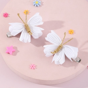 Handmade white satin butterfly hair clips with gold wire accents on pink display stand